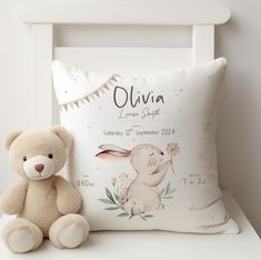 a teddy bear sitting next to a pillow on a white chair with the birth announcement