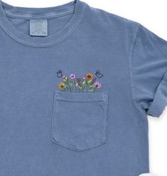 Comfort Colors Embroidered crewneck wildflower pocket tshirt. Embroidered flower shirt. Flower Boho Shirt. Gift for her or Girlfriend Gift. PLEASE NOTE THAT THE PICTURES ON THE LISTING ARE SAMPLES ONLY. If interested in adding embroidery to the sleeve please go to this listing: https://www.etsy.com/listing/1674502020 Because it is made to order, we don't accept the return or exchange unless we make a mistake We are unable to replace or refund purchases based on the color and the font selections. Floral Applique Short Sleeve Top In Relaxed Fit, Casual Crew Neck T-shirt With Floral Applique, Spring T-shirt With Pockets And Relaxed Fit, Casual Cotton T-shirt With Embroidered Patch, Spring Casual T-shirt With Floral Applique, Cute Crew Neck Top With Pockets, Blue Floral Embroidered Short Sleeve T-shirt, Summer Crew Neck T-shirt With Floral Applique, Summer Floral Applique T-shirt With Crew Neck