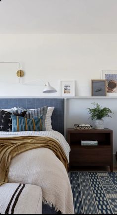 a bed room with a neatly made bed and some pictures on the wall above it