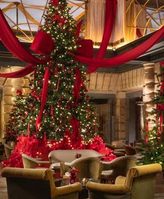 a christmas tree is decorated with red ribbons and bows in a lobby area at the holiday inn