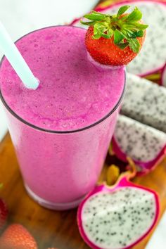 a smoothie in a glass with a strawberry on top and dragon fruit next to it