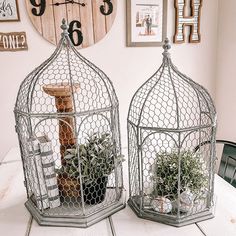 two metal cages with plants in them on top of a table next to a clock