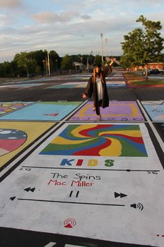 a woman standing in the middle of a parking lot painted with children's artwork