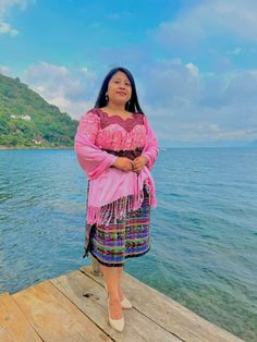 a woman standing on a dock next to the ocean with her arms crossed and eyes closed