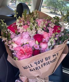 a bouquet of flowers sitting in the back seat of a car with a sign that says will you be my girlfriend?