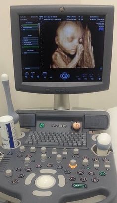 a computer monitor sitting on top of a table next to a cup and spoons