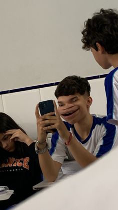 three people sitting at a table and one is holding up a cell phone to take a photo