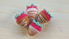 three crocheted strawberries sitting on top of a wooden table next to each other