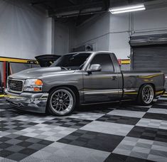 a silver truck parked in a garage next to a yellow and black checkered floor