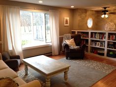 a living room filled with furniture and a book shelf in front of a large window