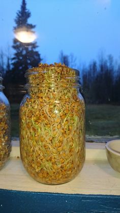 two jars filled with food sitting on top of a window sill