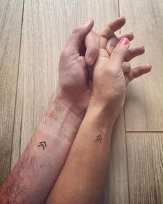 two people holding hands with tattoos on their arms and wrist, one has the letter t