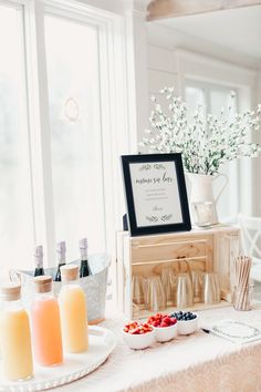 a table topped with bottles and plates filled with fruit on top of a white table cloth