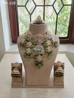 an elaborate necklace and matching earring set on display in front of a large window