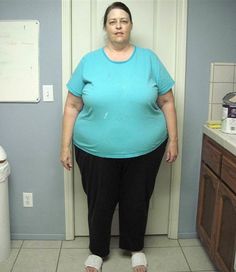 a woman standing in front of a bathroom door with her hands on her hips and looking at the camera