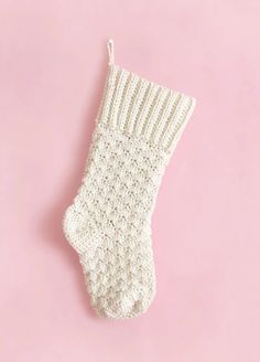 a white crocheted stocking on a pink background