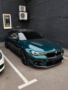 two cars parked in a parking space next to each other on the side of a building