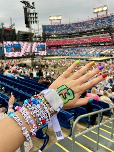 a woman's hand with bracelets and rings on it at a baseball game