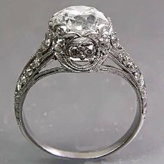 an antique style diamond ring with filigrees on the band and center stone