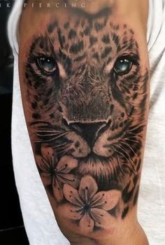 a black and white photo of a leopard with flowers on his arm