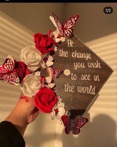 someone is holding some flowers in front of a graduation cap that says be the change you wish to see in the world