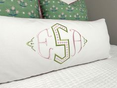 the monogrammed pillow is on top of the white bed with green and pink pillows