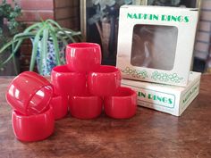 a stack of red cups sitting on top of a wooden table next to a box