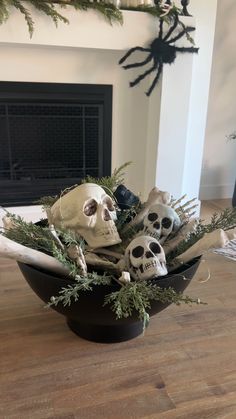 a bowl filled with fake skulls sitting on top of a wooden floor next to a fireplace