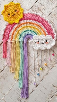 a crocheted rainbow with a smiling face on the side and tassels attached to it