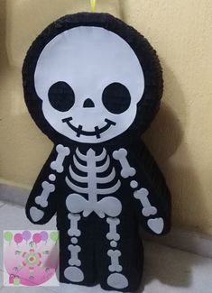 a stuffed toy with a skeleton on it's chest and arms, sitting in front of a wall