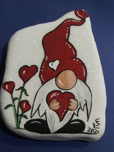 a painted rock with an image of a gnome holding a heart and flowers on it