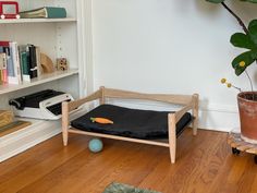 a dog bed sitting on top of a hard wood floor next to a book shelf