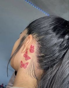 a woman with red butterfly tattoos on her left side of the head and behind her ear