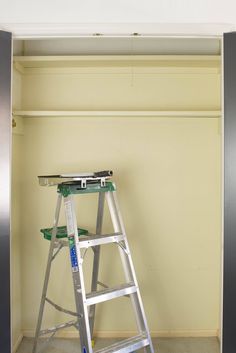 a ladder leaning up against a wall next to a shelf with some tools on it