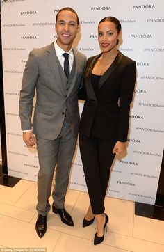 a man and woman standing next to each other in front of a wall with pandada on it