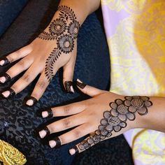 two women's hands with henna tattoos on them