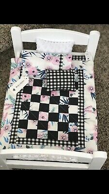 a doll bed with a black and white checkerboard quilt on it's back