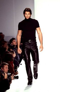 a male model walking down the runway in black leather pants and a turtle neck t - shirt