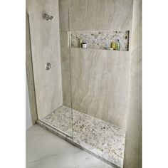 a walk in shower sitting next to a white tiled wall and floor with shelves on each side