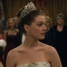 a woman wearing a tiara standing next to other people in formal dress and looking off into the distance