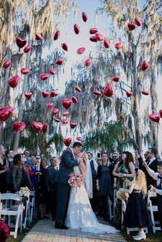 a bride and groom kissing under red paper lanterns at their outdoor wedding in charleston, sc