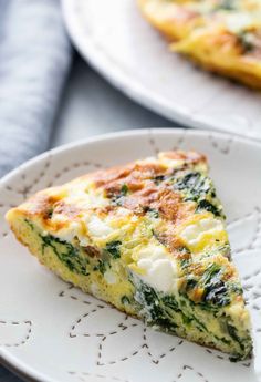 a slice of quiche with spinach and cheese sits on a plate next to another dish