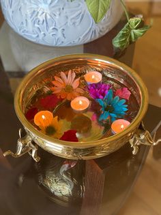 a metal bowl filled with flowers on top of a table