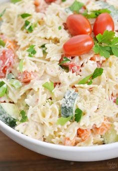 a white bowl filled with pasta salad topped with cherry tomatoes and parmesan cheese