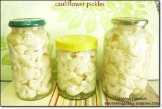 three jars filled with white cauliflower sitting on top of a striped table cloth