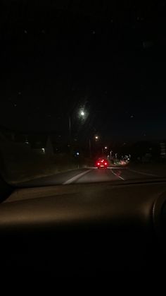 the dashboard of a car at night with street lights in the distance and dark sky