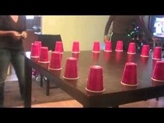 a group of people standing around a table with red cups on it and one person in the background