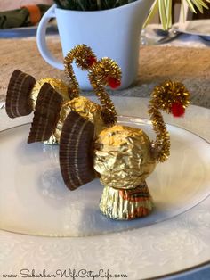 a plate topped with chocolate candy covered in gold foil next to a cup filled with flowers