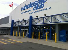 the front entrance of a whole safe club store with cars parked outside it and canadian flag flying in the background