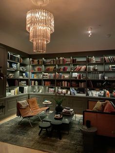 a living room filled with furniture and a chandelier hanging above the bookshelf